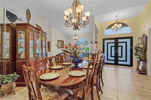 tiled dining space featuring french doors, a chandelier, and vaulted ceiling