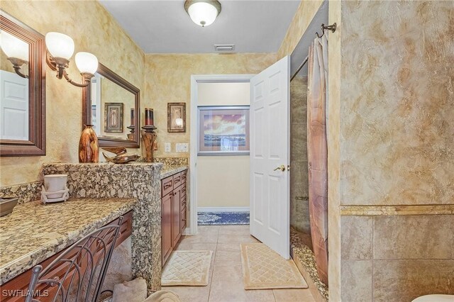 bathroom with a shower, tile patterned flooring, and vanity