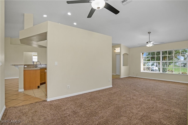 unfurnished living room with ceiling fan, light colored carpet, and sink