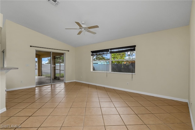 empty room featuring ceiling fan, vaulted ceiling, light tile patterned flooring, and plenty of natural light