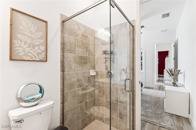 bathroom with an enclosed shower, hardwood / wood-style flooring, and toilet