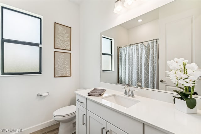 bathroom with hardwood / wood-style flooring, vanity, a shower with shower curtain, and toilet