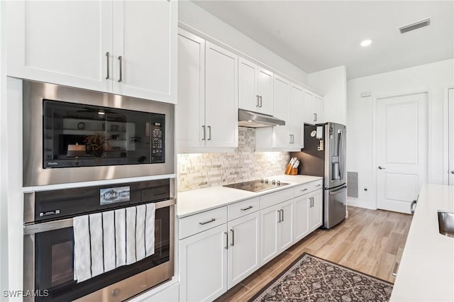 kitchen featuring white cabinetry, backsplash, light hardwood / wood-style flooring, and black appliances