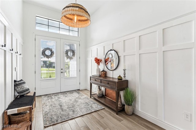 foyer entrance with french doors, a high ceiling, and light wood-type flooring