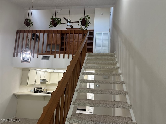 stairs with carpet floors and ceiling fan