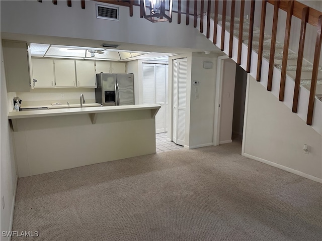 kitchen with white cabinetry, kitchen peninsula, stainless steel fridge with ice dispenser, and light carpet