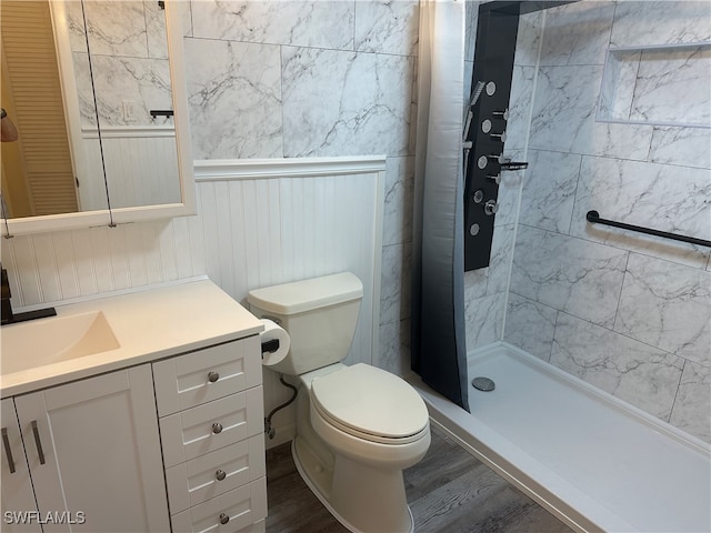 bathroom with toilet, vanity, hardwood / wood-style floors, and a tile shower