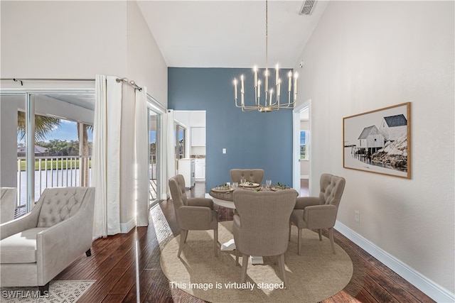 dining area with dark wood-type flooring, high vaulted ceiling, a notable chandelier, and a water view