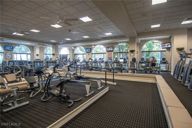 gym featuring ceiling fan, a paneled ceiling, and a wealth of natural light