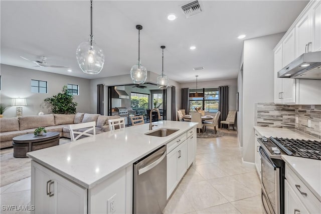 kitchen featuring appliances with stainless steel finishes, white cabinets, sink, and a center island with sink