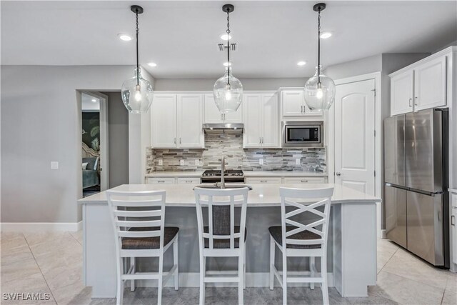 kitchen with stainless steel appliances, white cabinetry, a kitchen island with sink, and hanging light fixtures