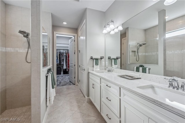 bathroom with vanity, tiled shower, and tile patterned flooring