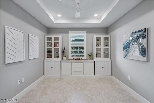 bar with white cabinetry and a tray ceiling