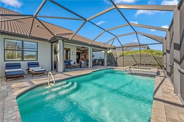 view of pool with ceiling fan, a patio area, glass enclosure, and an in ground hot tub