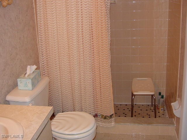 bathroom with toilet, a shower with shower curtain, tile patterned floors, and vanity