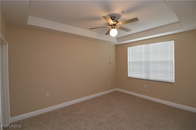 carpeted empty room with ceiling fan and a raised ceiling