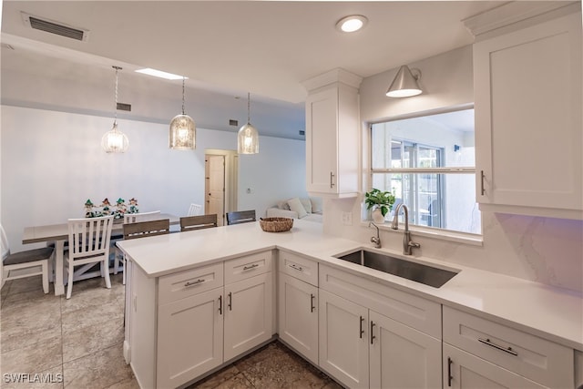 kitchen with pendant lighting, white cabinetry, kitchen peninsula, and sink