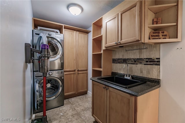 clothes washing area featuring cabinets, stacked washing maching and dryer, and sink