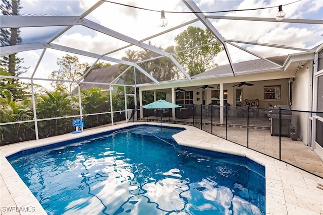 view of pool with a patio, glass enclosure, and ceiling fan