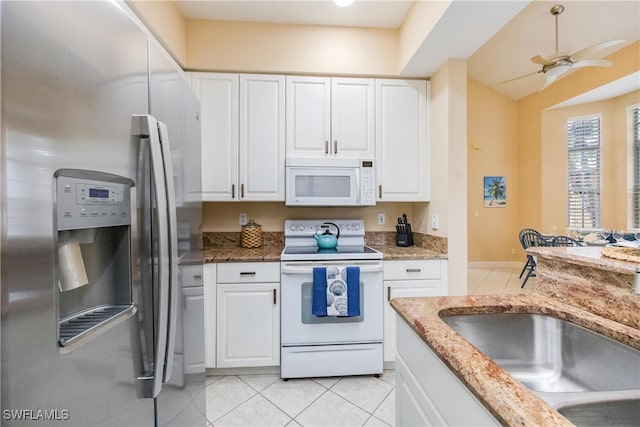 kitchen featuring white appliances, white cabinets, ceiling fan, a sink, and light tile patterned flooring