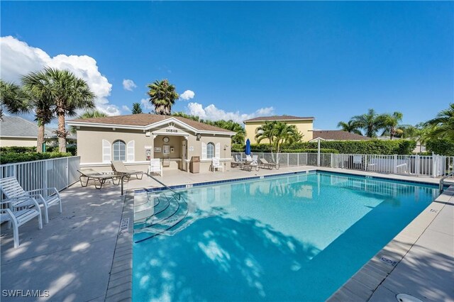 community pool with a patio area and fence