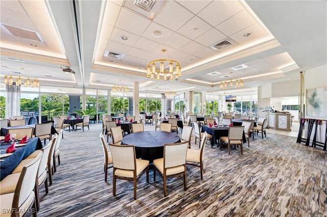 dining area with a chandelier, a raised ceiling, and visible vents