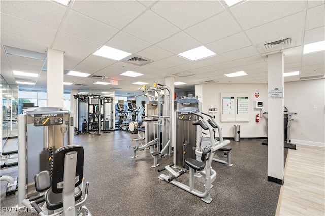 exercise room featuring a paneled ceiling, baseboards, and visible vents