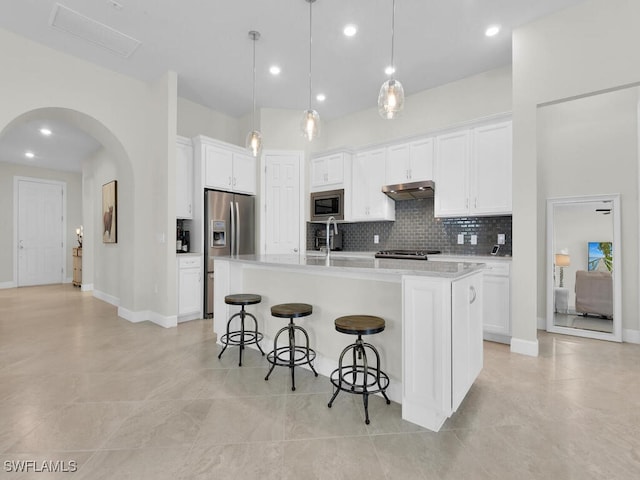 kitchen featuring white cabinetry, a center island with sink, hanging light fixtures, appliances with stainless steel finishes, and a breakfast bar area