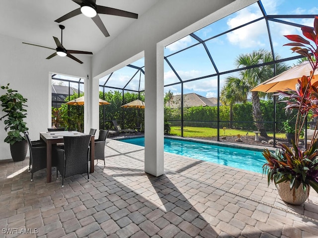 view of swimming pool with a patio, glass enclosure, and ceiling fan