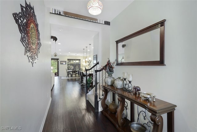 hall featuring dark wood-type flooring and a notable chandelier