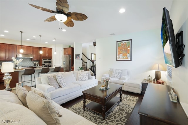 living room with dark wood-type flooring, ceiling fan, and sink