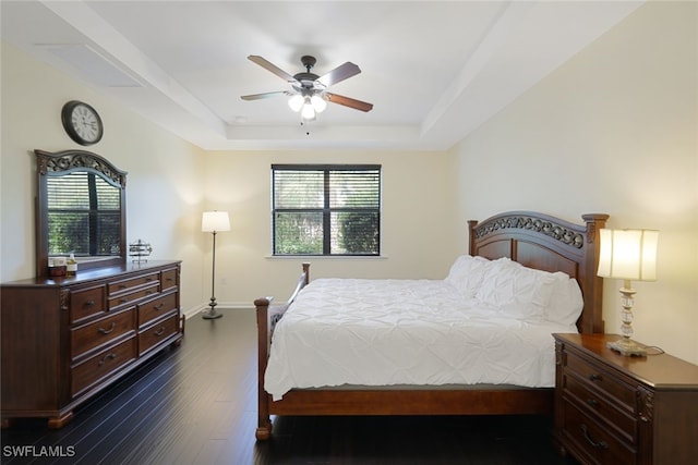 bedroom featuring ceiling fan, dark hardwood / wood-style floors, and a raised ceiling