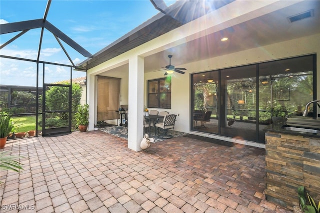 view of patio with glass enclosure, grilling area, ceiling fan, and sink