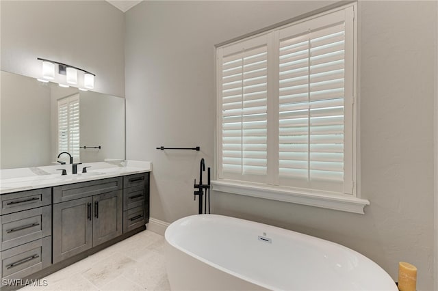 bathroom featuring tile patterned flooring, a bathtub, vanity, and plenty of natural light