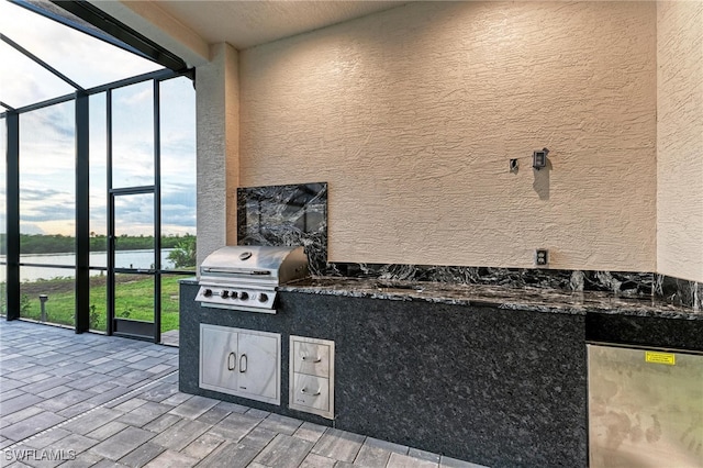 view of patio / terrace with glass enclosure, a water view, exterior kitchen, and a grill