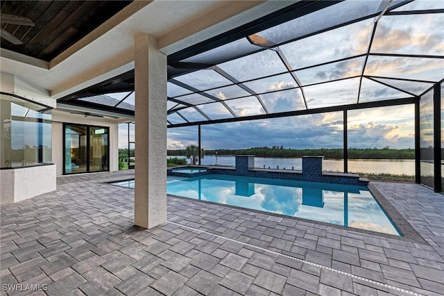 view of swimming pool featuring a patio area, a water view, a lanai, and an in ground hot tub