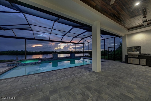 pool at dusk with glass enclosure, an in ground hot tub, a patio area, grilling area, and a water view