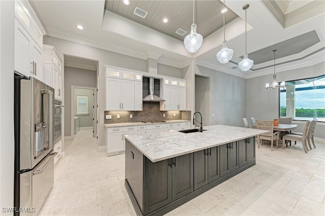 kitchen with stainless steel appliances, hanging light fixtures, white cabinetry, and a center island with sink