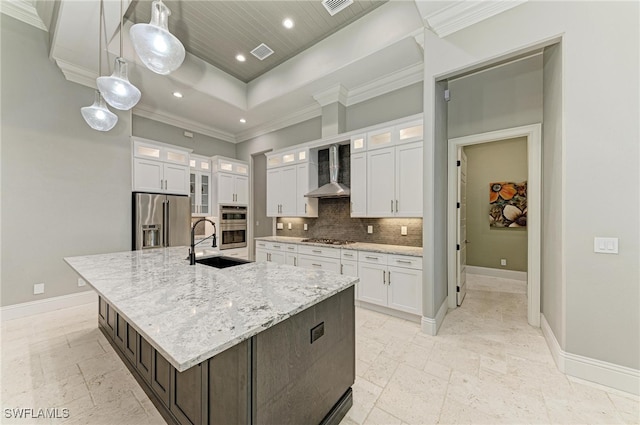 kitchen featuring stainless steel appliances, a center island with sink, white cabinets, wall chimney exhaust hood, and hanging light fixtures