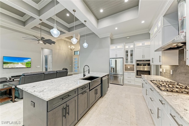 kitchen featuring stainless steel appliances, a center island with sink, white cabinets, wall chimney exhaust hood, and coffered ceiling