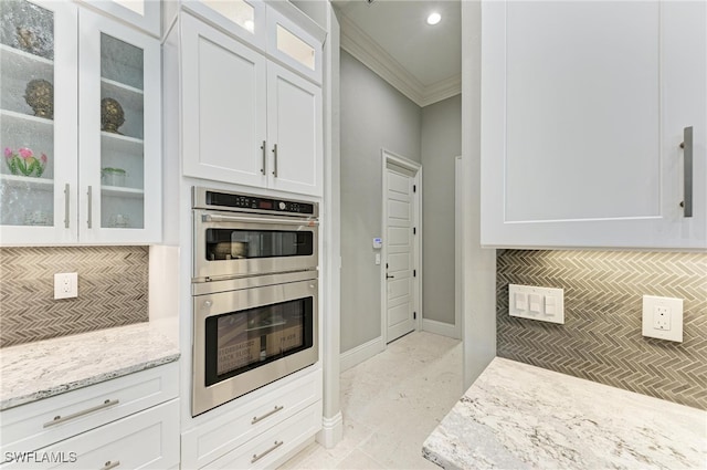 kitchen featuring white cabinets, stainless steel double oven, decorative backsplash, and light stone counters