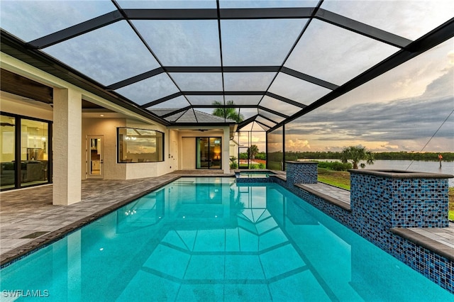 pool at dusk featuring a lanai and a patio area