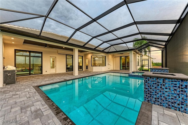 view of swimming pool featuring glass enclosure, a patio, and ceiling fan