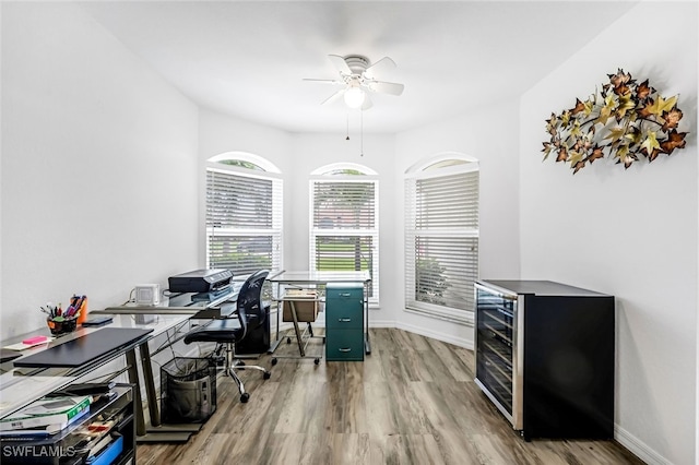 office space with ceiling fan, light wood-type flooring, and beverage cooler