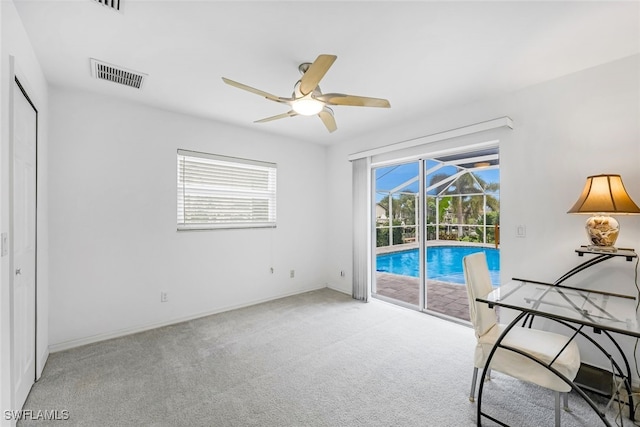 interior space with access to exterior, light carpet, multiple windows, and ceiling fan