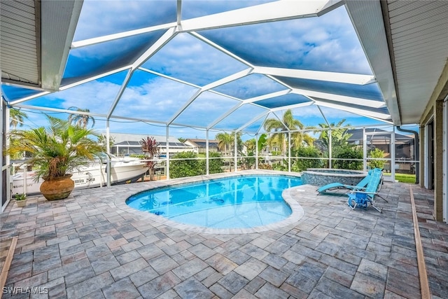 view of pool featuring glass enclosure, an in ground hot tub, and a patio