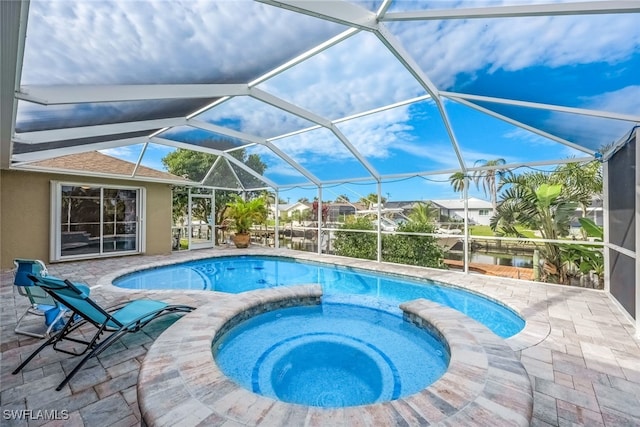 view of pool featuring glass enclosure, a patio area, and an in ground hot tub