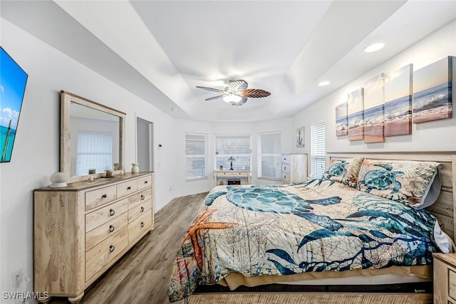 bedroom with hardwood / wood-style floors, ceiling fan, and multiple windows