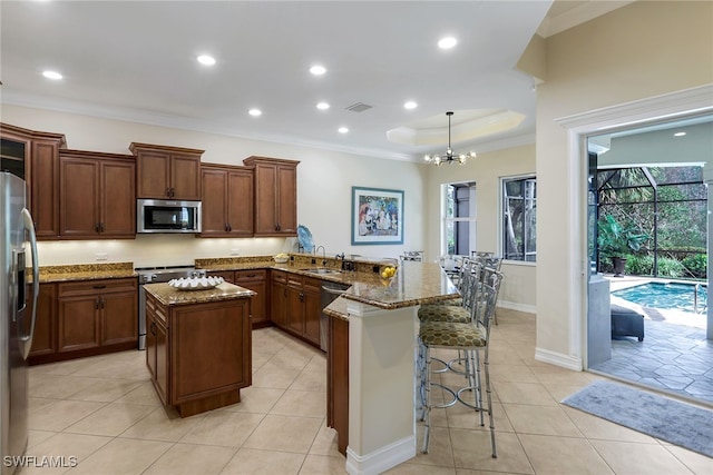 kitchen with stainless steel appliances, kitchen peninsula, hanging light fixtures, sink, and a breakfast bar