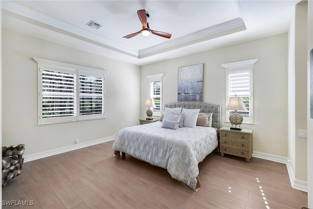 bedroom featuring hardwood / wood-style flooring, ceiling fan, and a tray ceiling